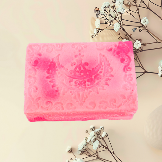 Pink soap bar with decorative design on a beige background with small white flowers.
