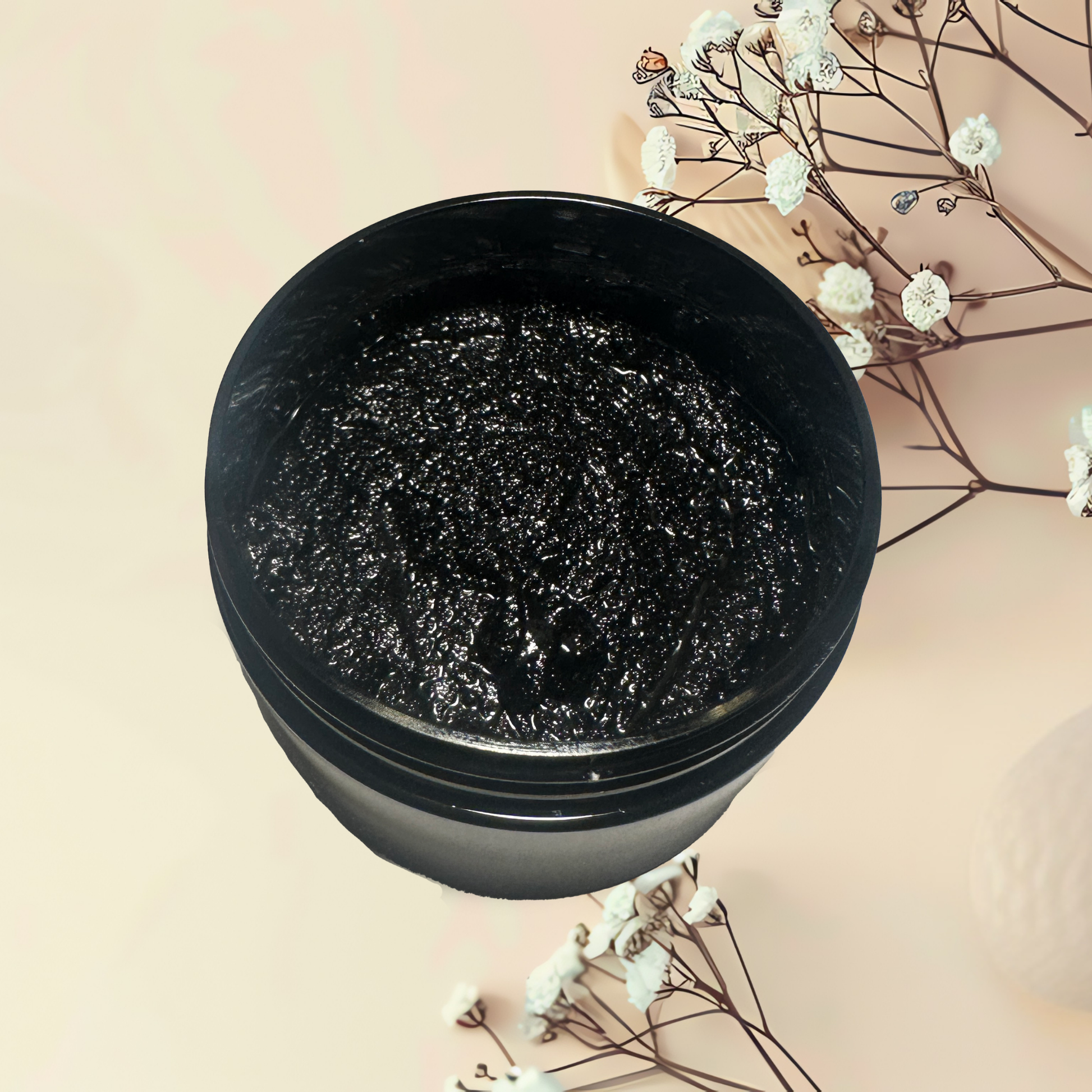 Black jar of cosmetic scrub with decorative flowers on a beige background
