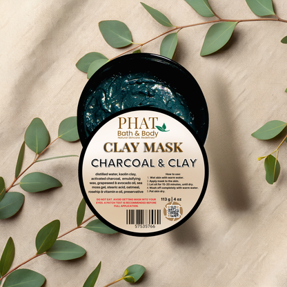 Jar of Phat Bath & Body Charcoal & Clay Mask with green leaves on a beige fabric background