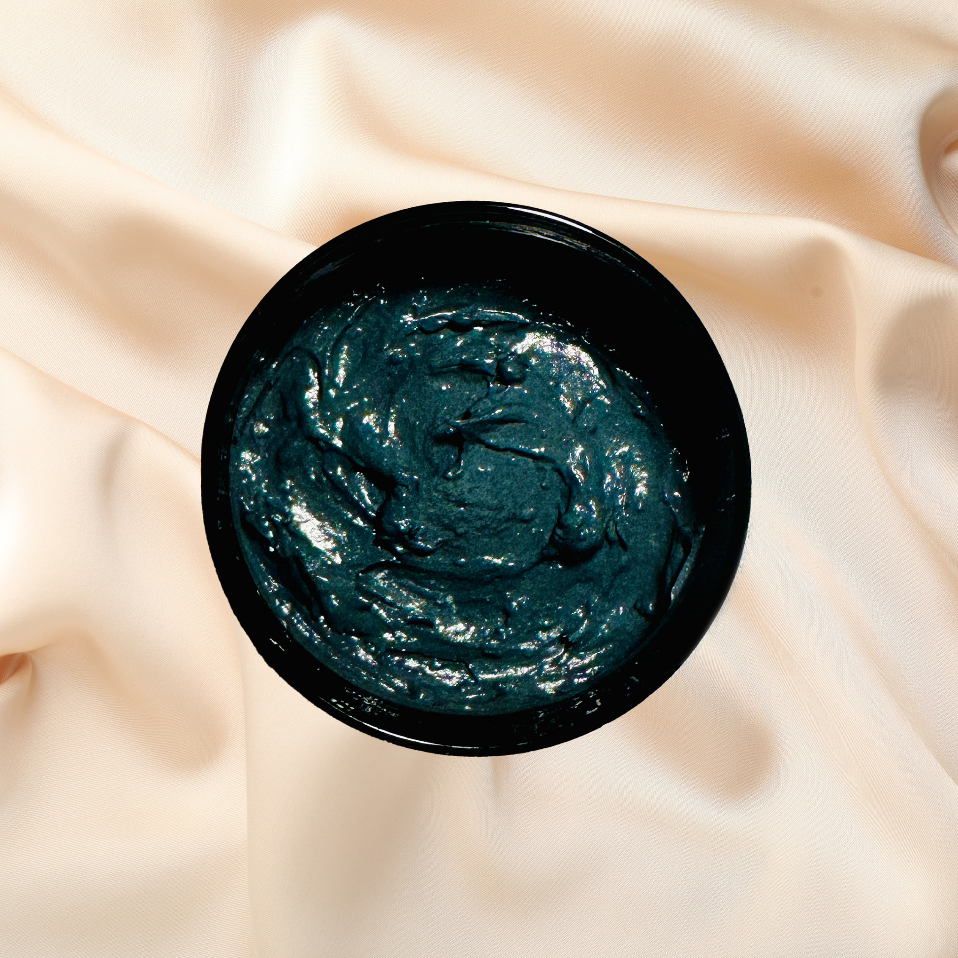 Black container of charcoal mask on a beige fabric background