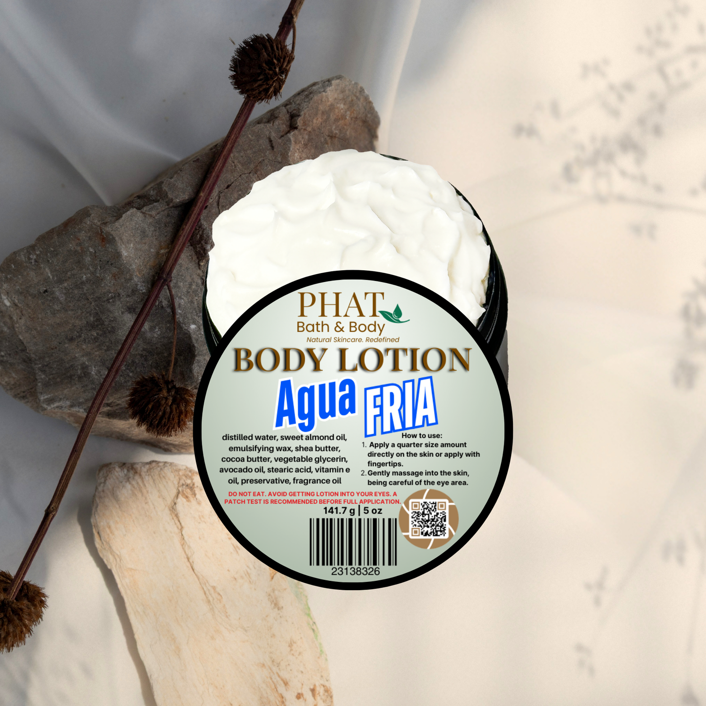 Body lotion container labeled 'Agua Fria' by Phat Bath & Body on a natural stone background.