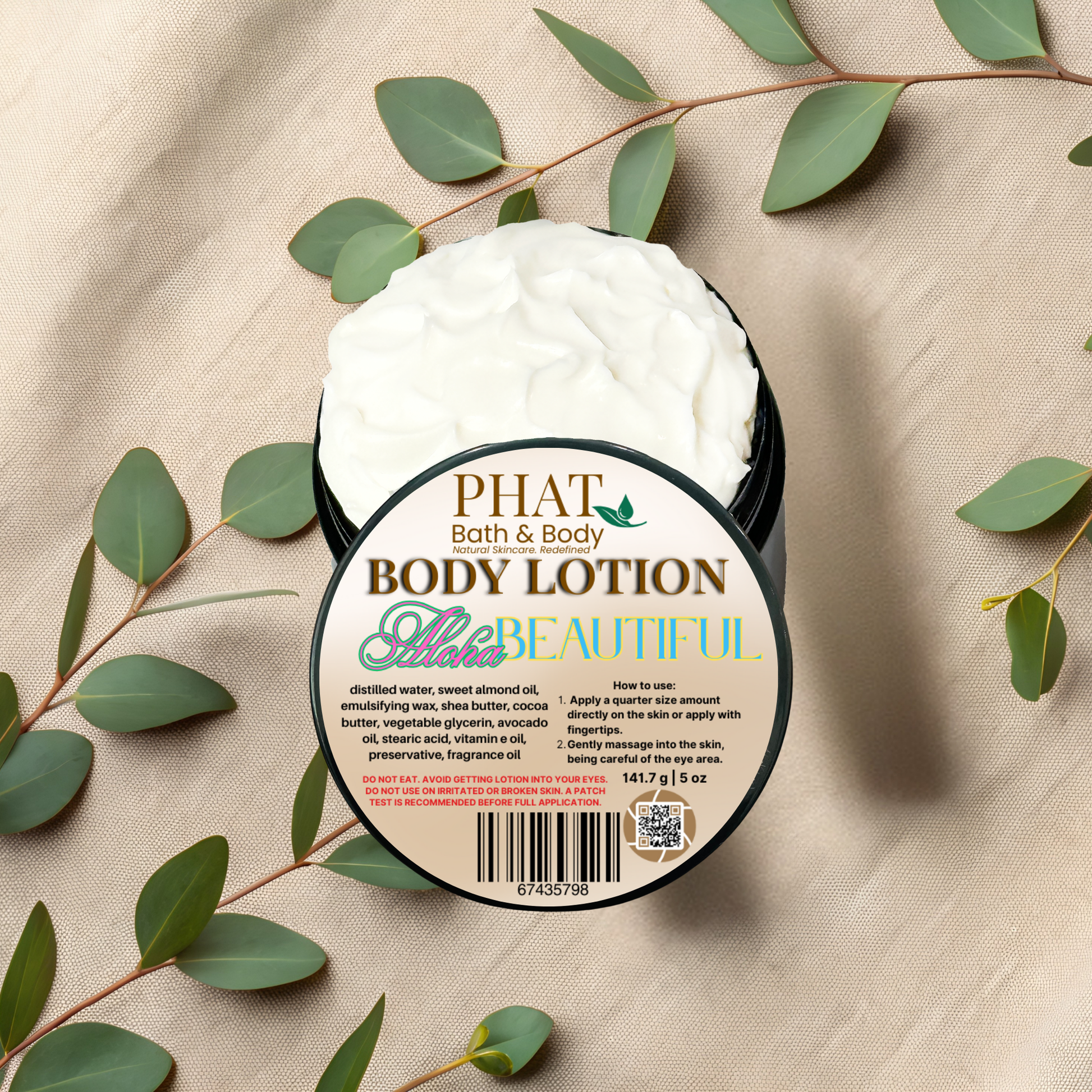 Body lotion container with 'PHAT Bath & Body' label on a beige fabric background with green leaves.