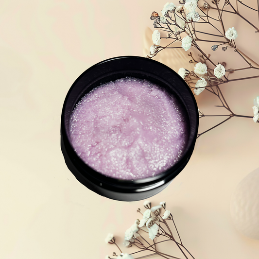 Black bowl with purple scrub on a beige background with white flowers