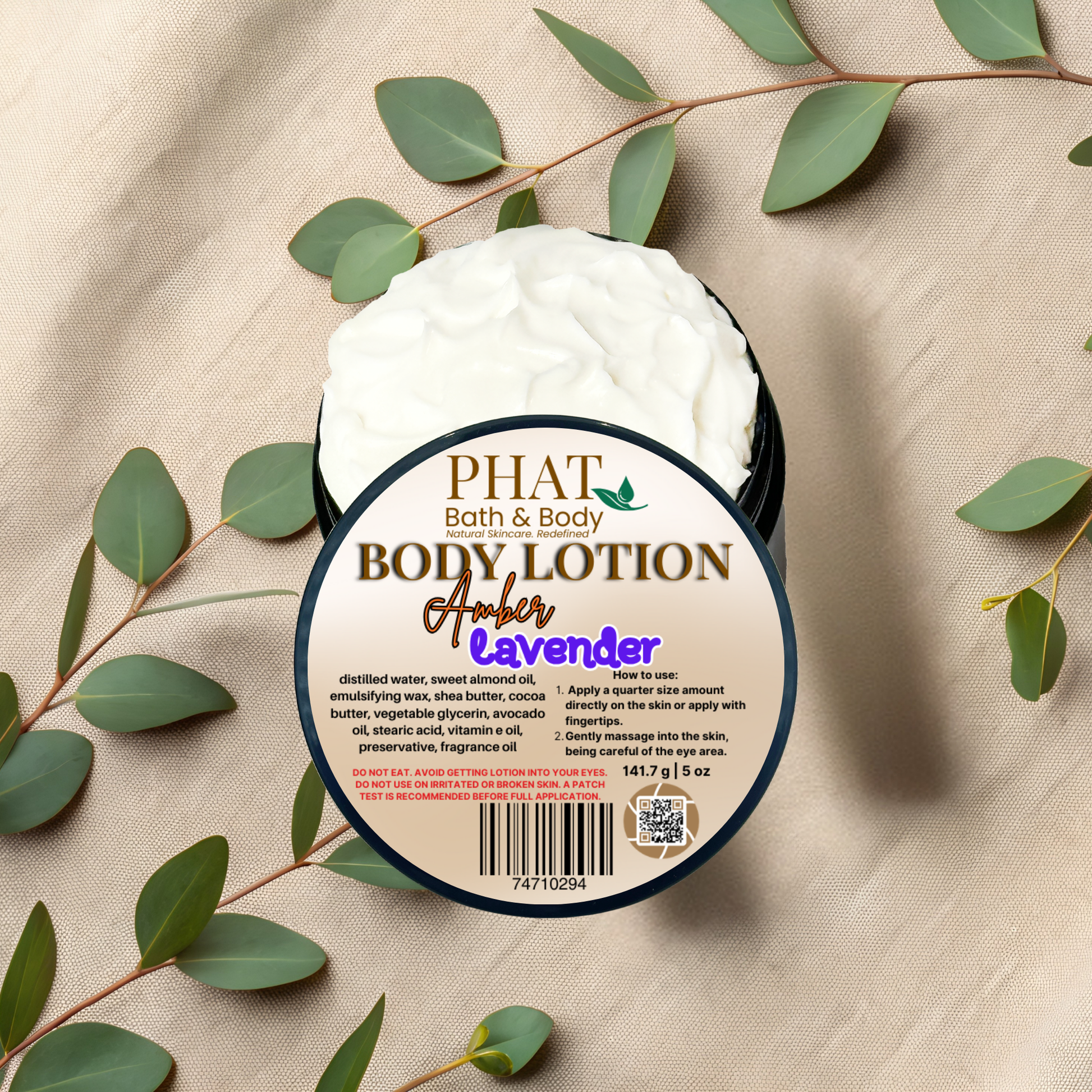 Body lotion container with 'Phat Bath & Body' branding on a beige fabric background with green leaves.