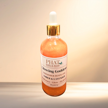 Bottle of 'Glowing Goddess' shimmer body oil from PHAT Bath & Body on a neutral background