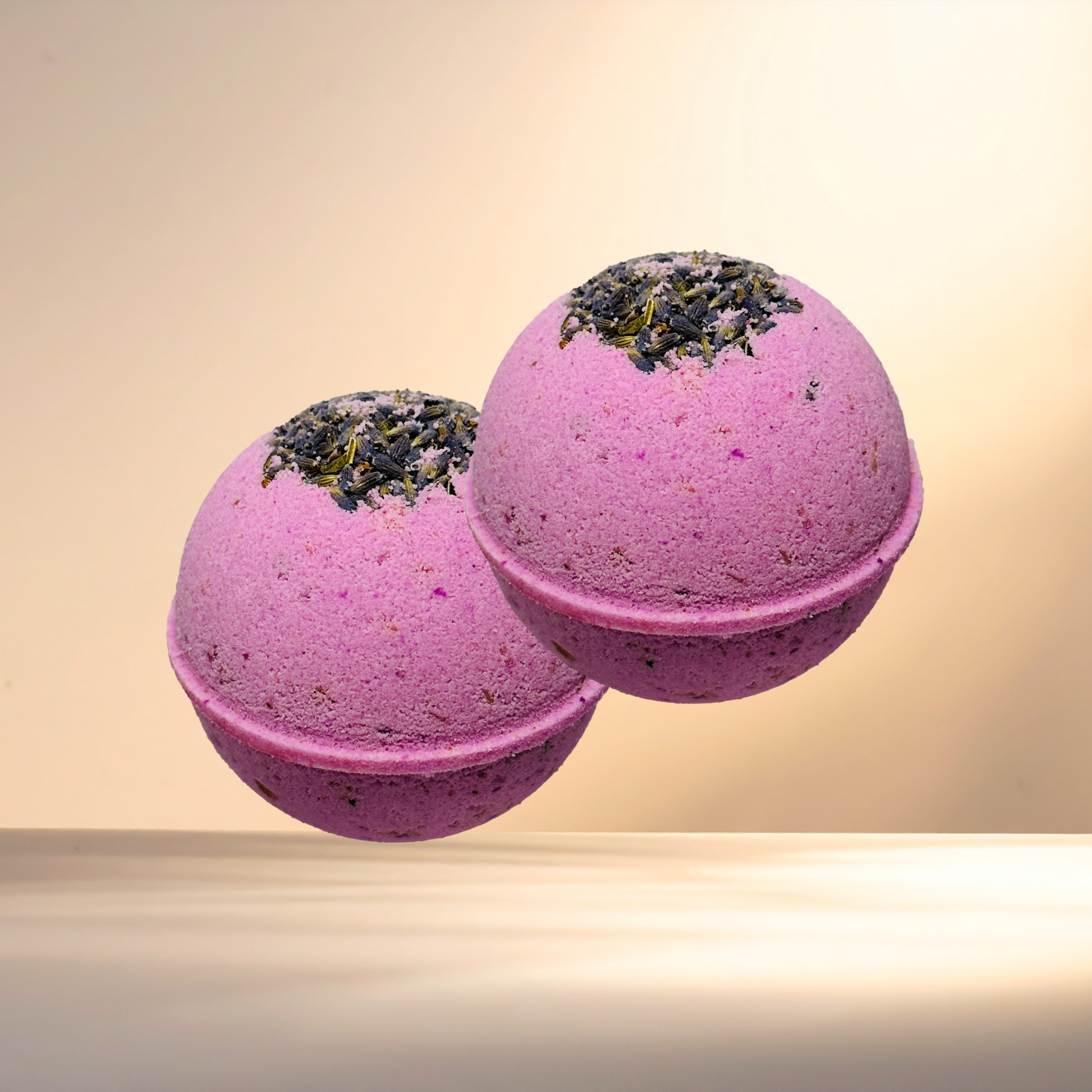 Two purple bath bombs with greenery on top against a beige background