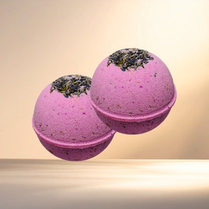 Two purple bath bombs with greenery on top against a beige background