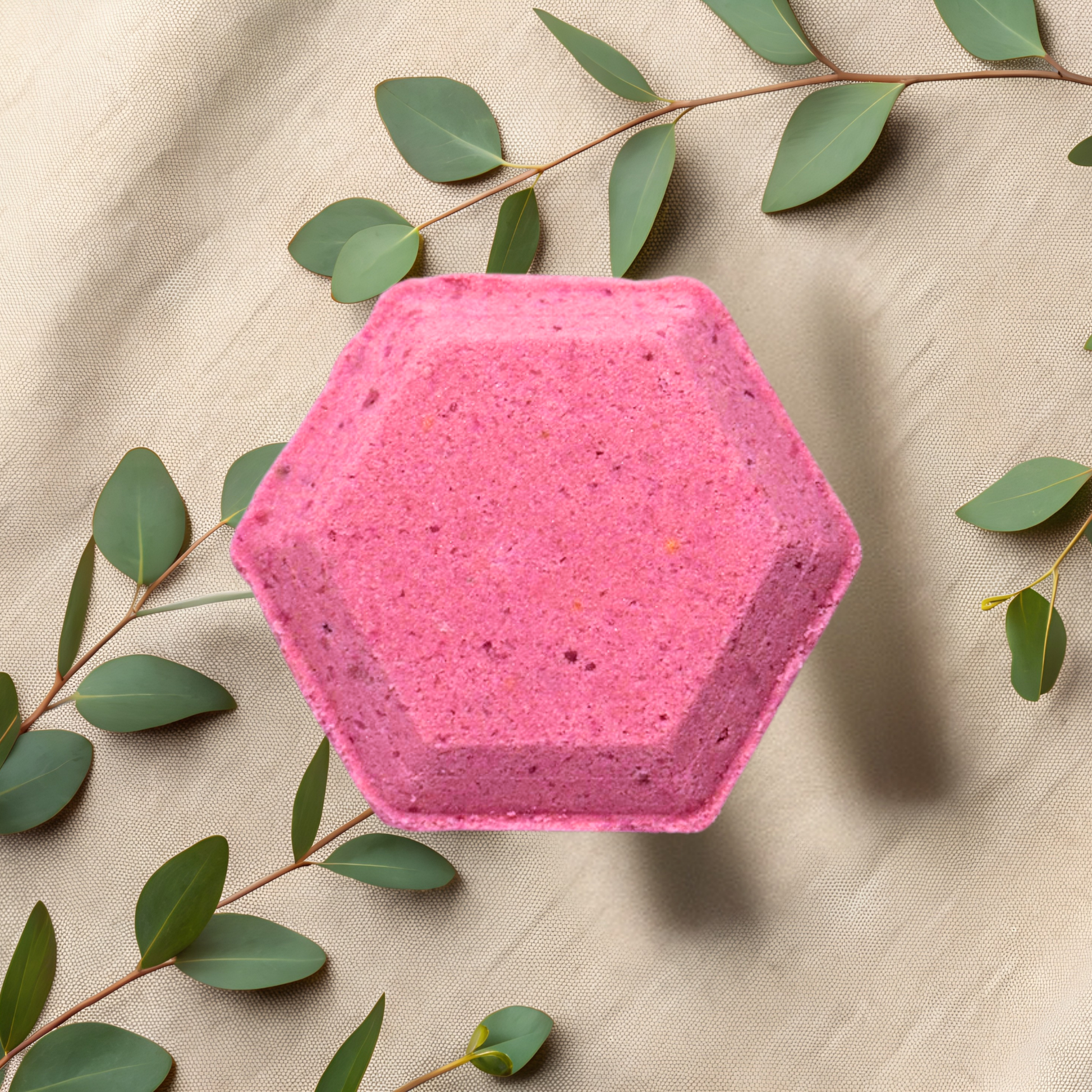 Hexagonal pink shower bomb with green leaves on a beige fabric background