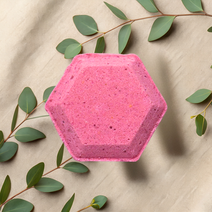 Hexagonal pink shower bomb with green leaves on a beige fabric background