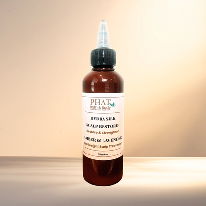 A bottle of PHAT Bath & Body Hydra Silk Scalp Restore + Amber & Lavender lightweight scalp treatment, in an amber bottle with a black cap and white label, set against a warm beige background.