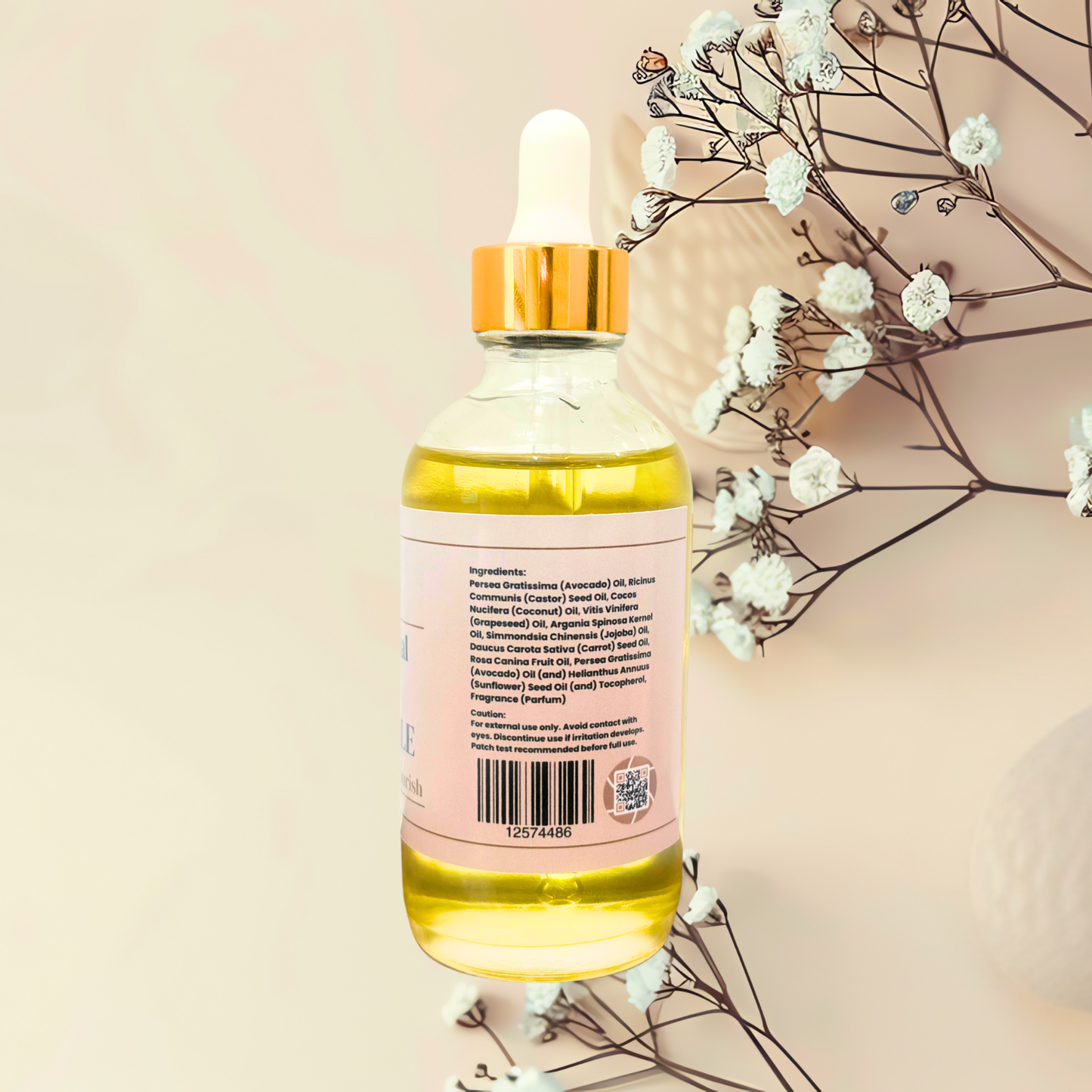 A glass dropper bottle of golden-yellow cosmetic oil with a gold cap and a pale pink label, shown against a soft beige background with delicate white flowers.