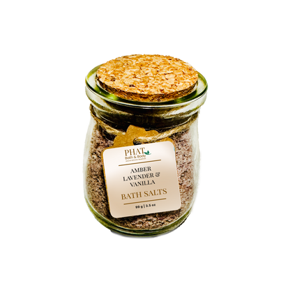 Jar of amber lavender and vanilla bath salts with a cork lid on a white background