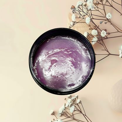 Purple scrub in a black container with white flowers on a beige background