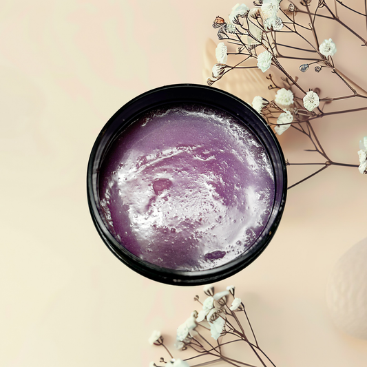 Purple scrub in a black container with white flowers on a beige background