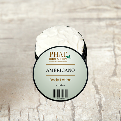 An open round tub of PHAT Bath & Body 'Americano' body lotion, showing the white cream inside, set against a light beige stone-textured background.