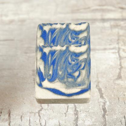 Bar of soap with blue and white swirl pattern on a textured beige background