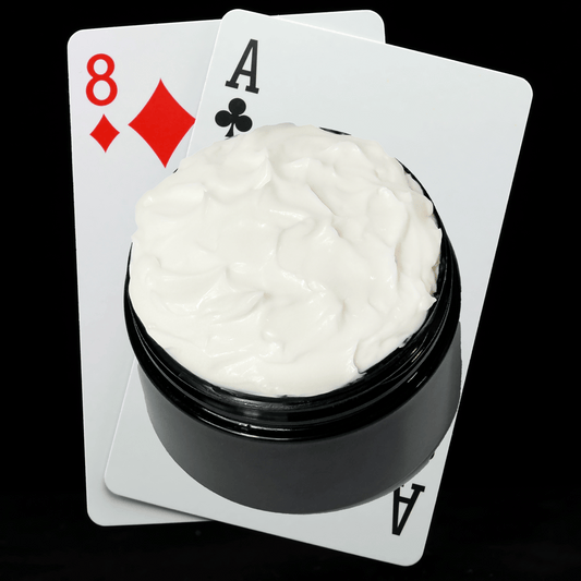 Black jar of cream with playing cards showing an Ace and an Eight on a white background