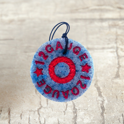 Round blue and red freshie with '12 Gauge' text on a textured beige background