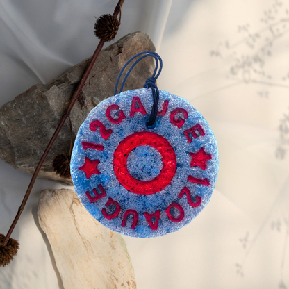 Decorative round freshie with red and blue design on a white background