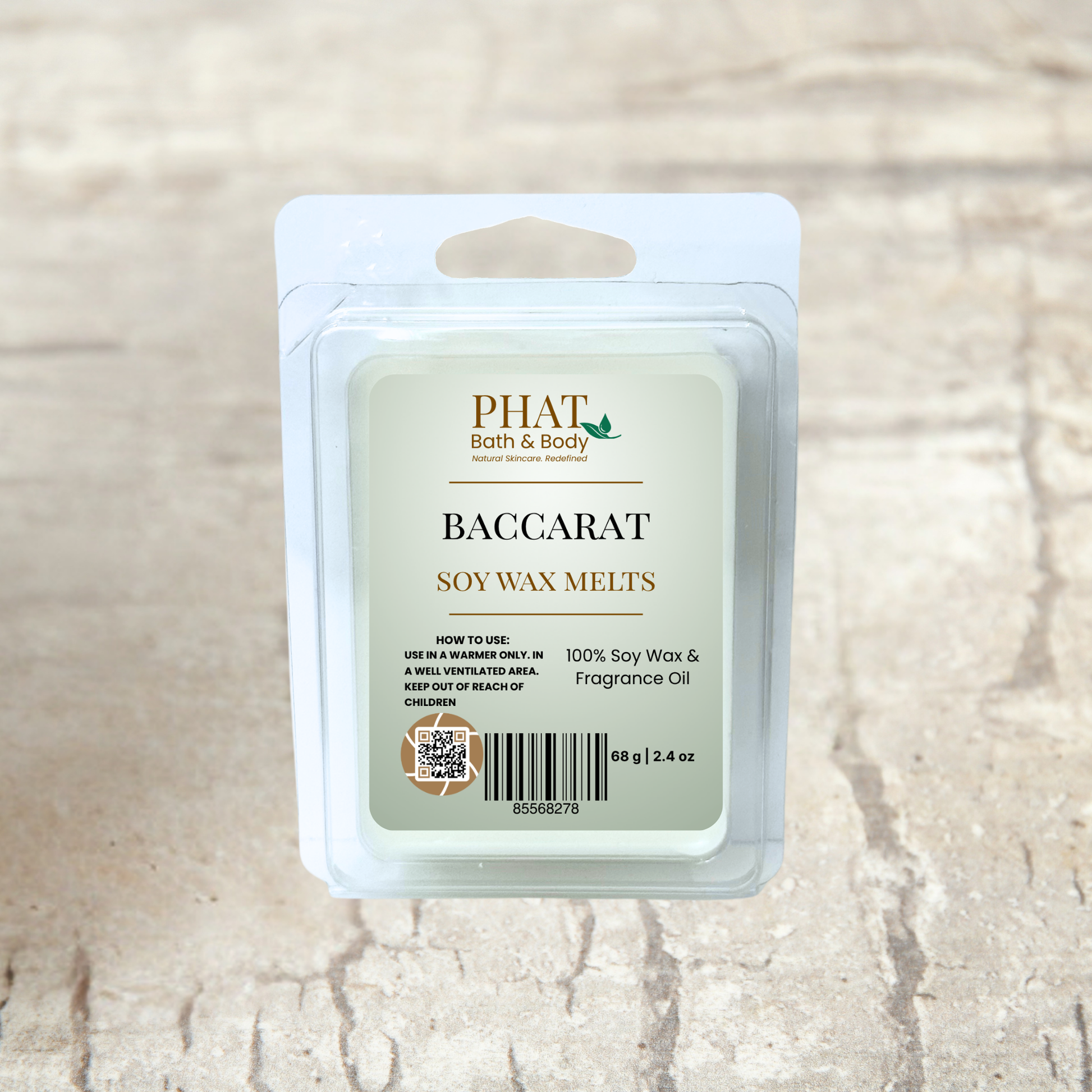 PHAT Bath & Body baccarat soy wax melts packaging on a beige fabric background with green leaves.
