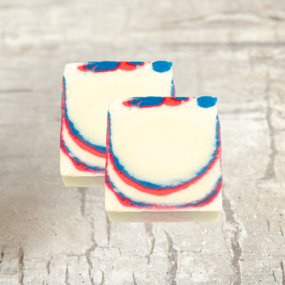Two bars of soap with red, white, and blue swirls on a textured surface