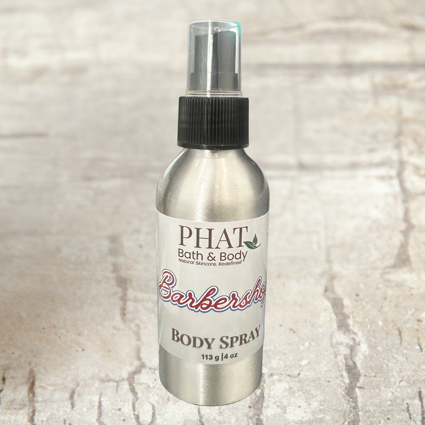 Body spray bottle labeled 'PHAT Bath & Body' on a textured beige background