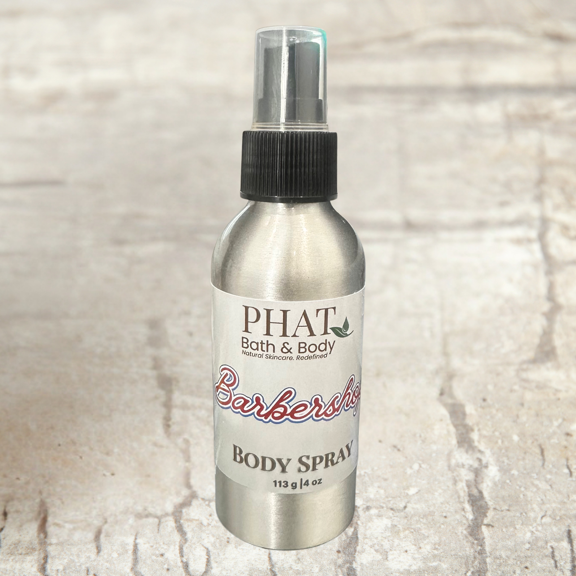 Body spray bottle labeled 'PHAT Bath & Body' on a textured beige background