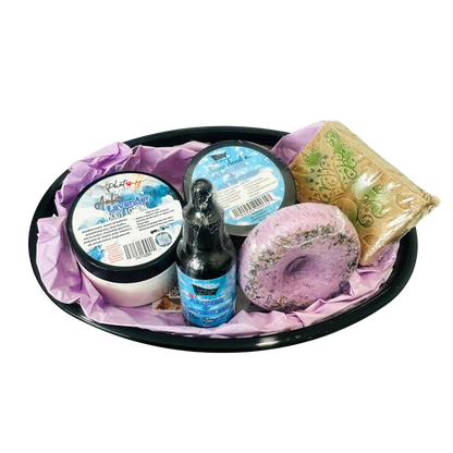 Bath and body set with a bottle, jar, and soap on a black tray with purple tissue paper.