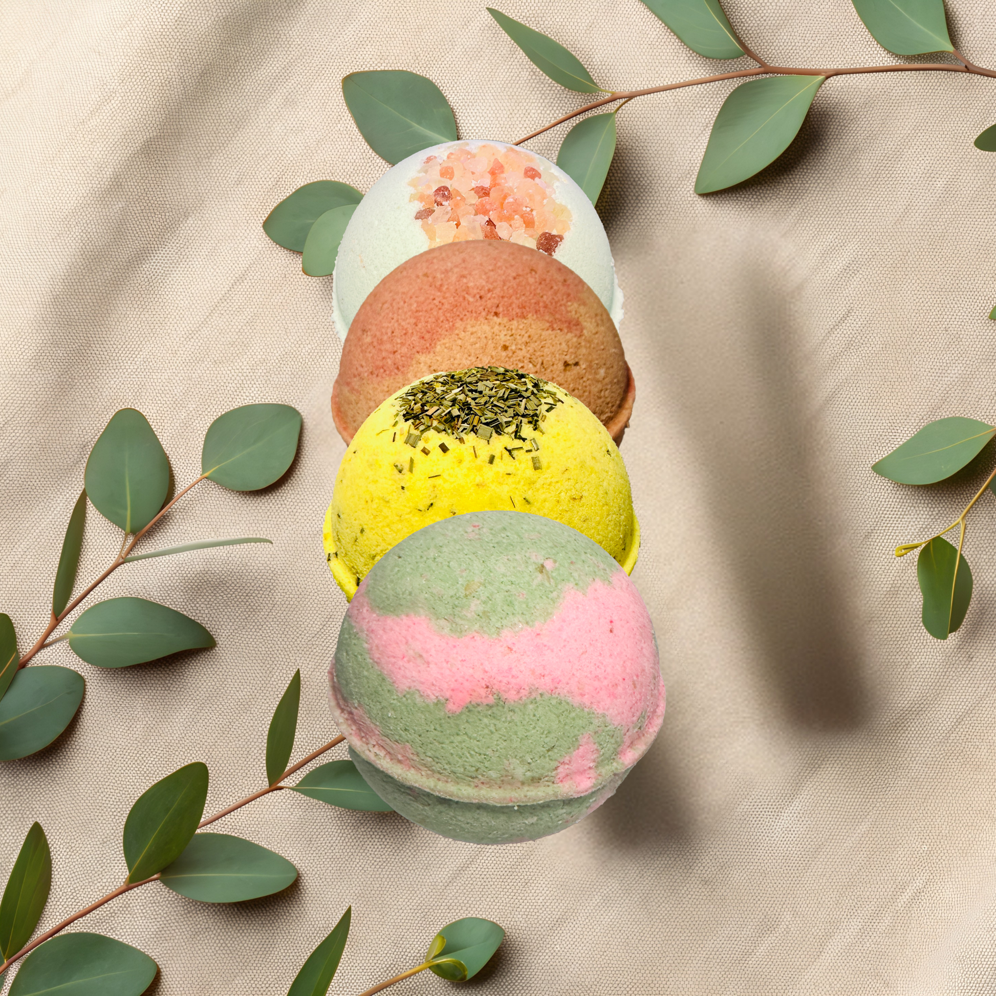 Colorful bath bombs with green leaves on a beige fabric background