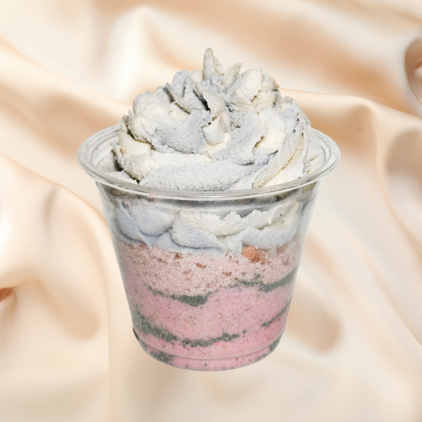 Marbled bath parfait in a clear cup on a beige fabric background