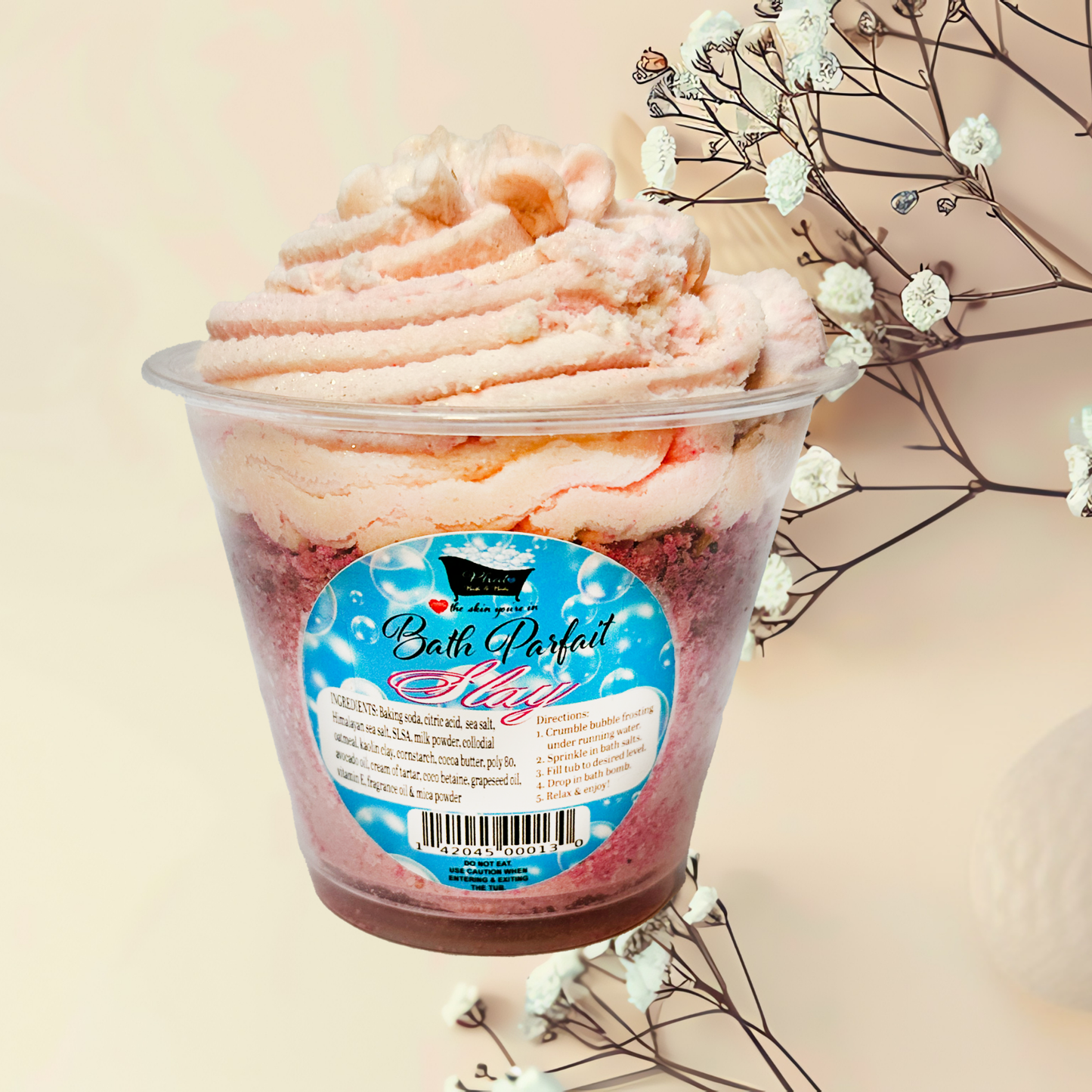 Bath parfait in a clear container with a decorative label on a light background