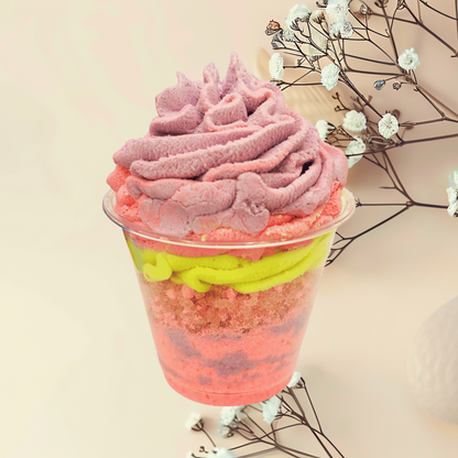 Colorful layered bath parfait in a transparent cup with a light background