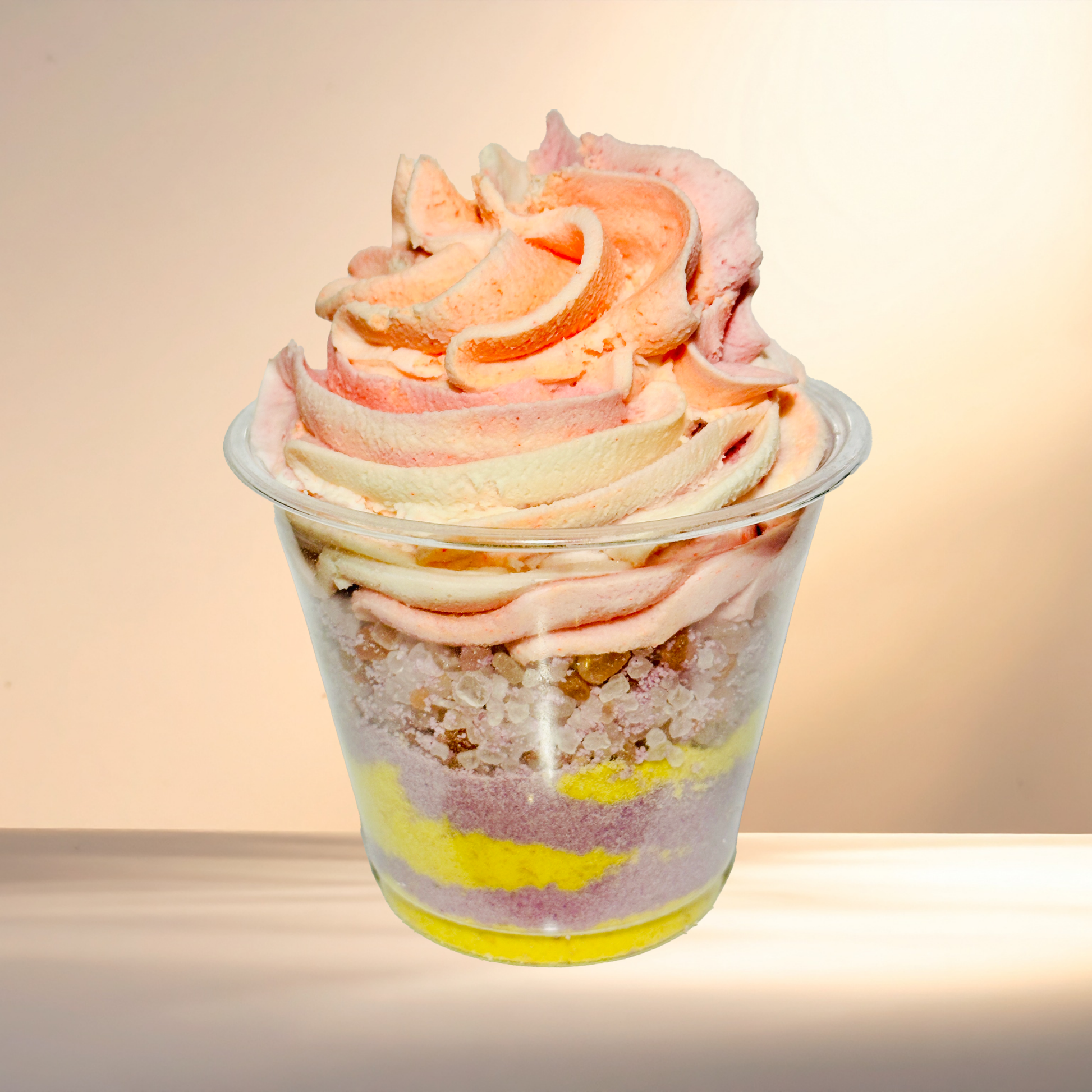 Colorful layered bubble bomb in a transparent cup with a soft focus background