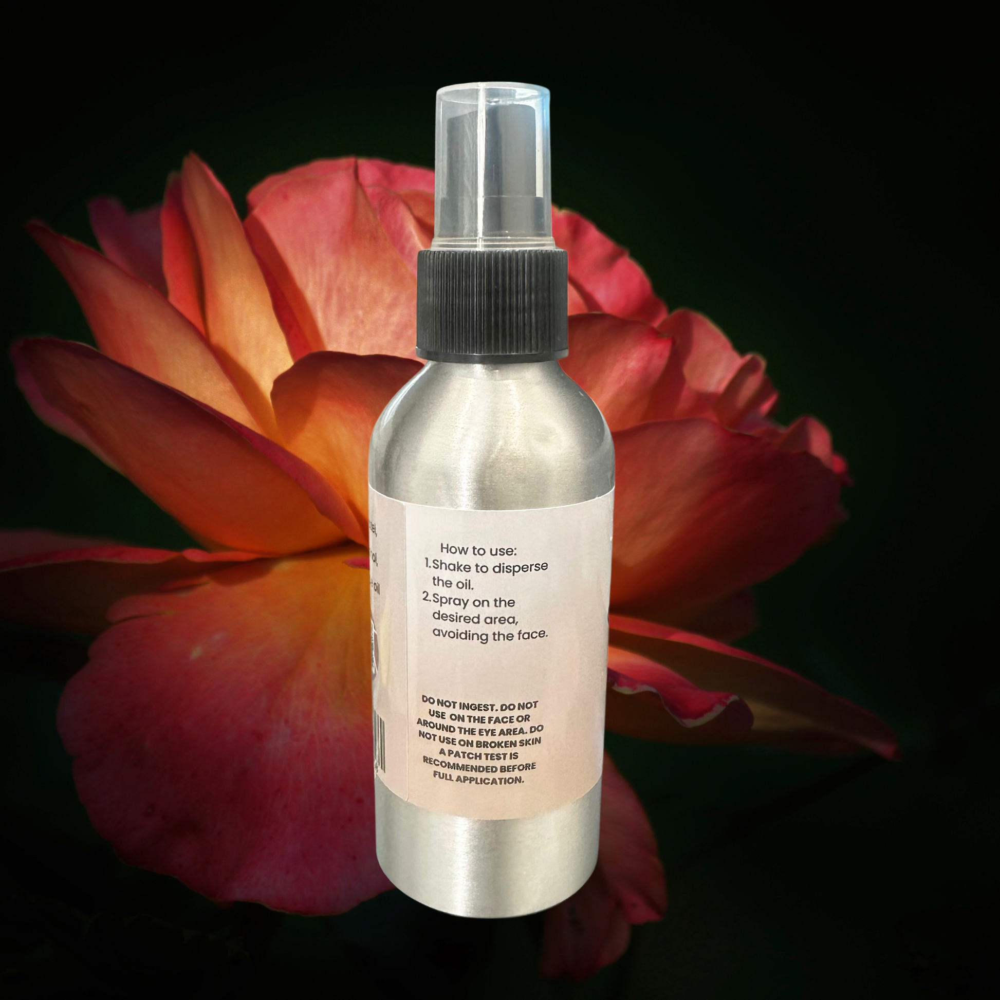Spray bottle with label against a dark background with a red flower