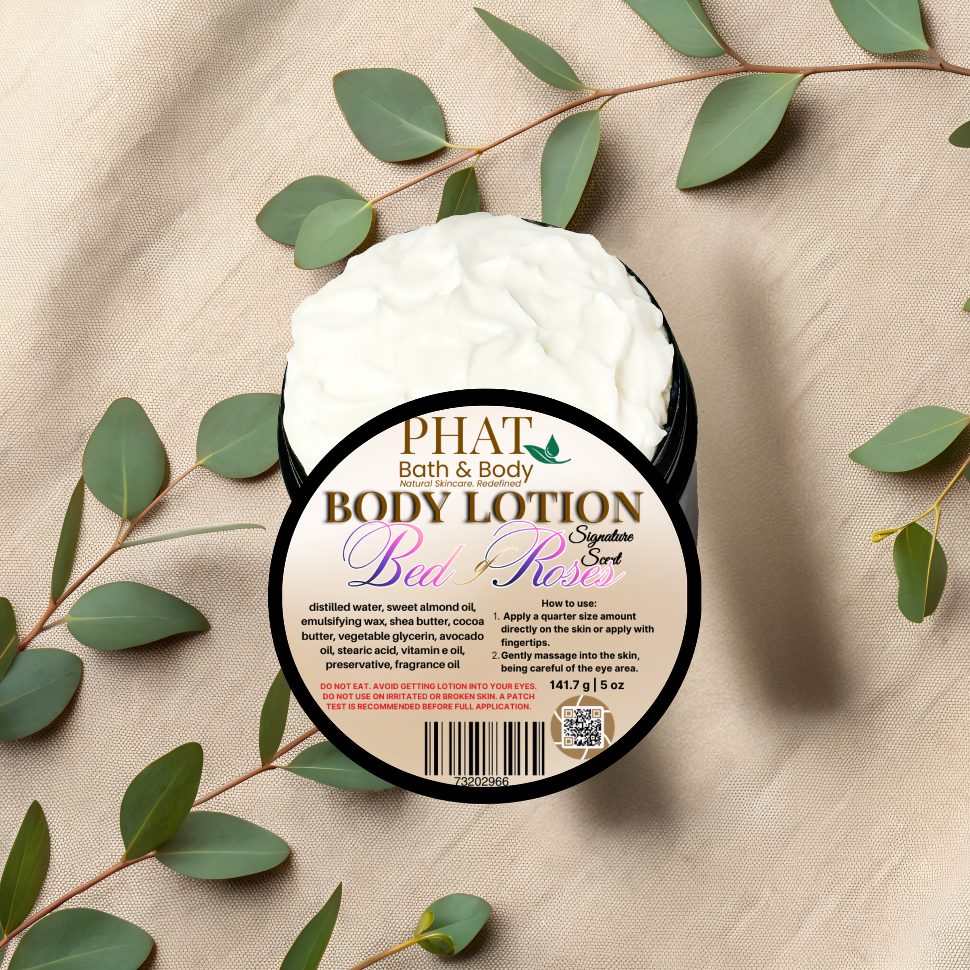 Body lotion container with 'Phat Bath & Body' label on a beige fabric background with green leaves.