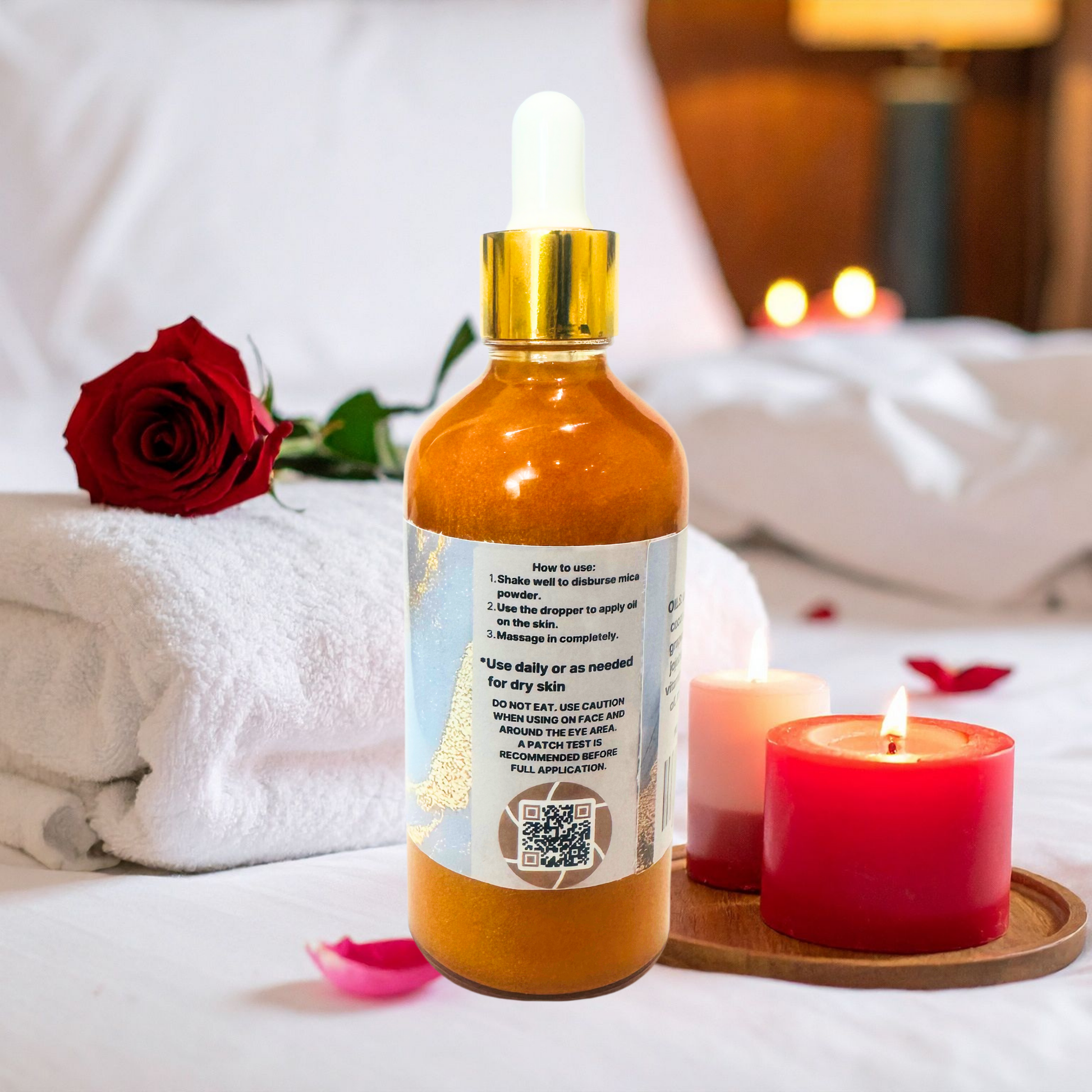 Bottle of skincare shimmer body oil with dropper on a tray with candles and a rose on a bed.