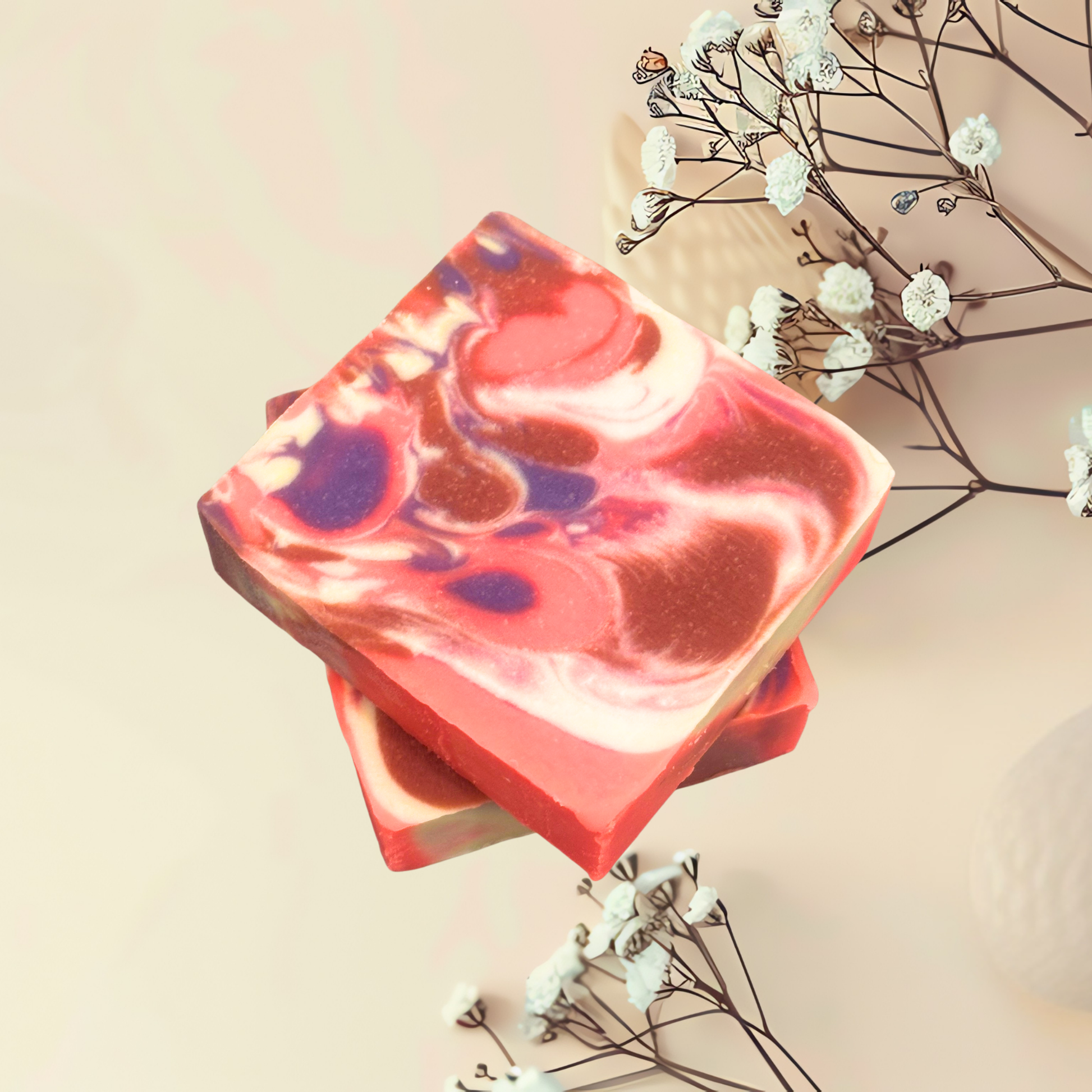 Two colorful soap bars with a floral arrangement on a light background