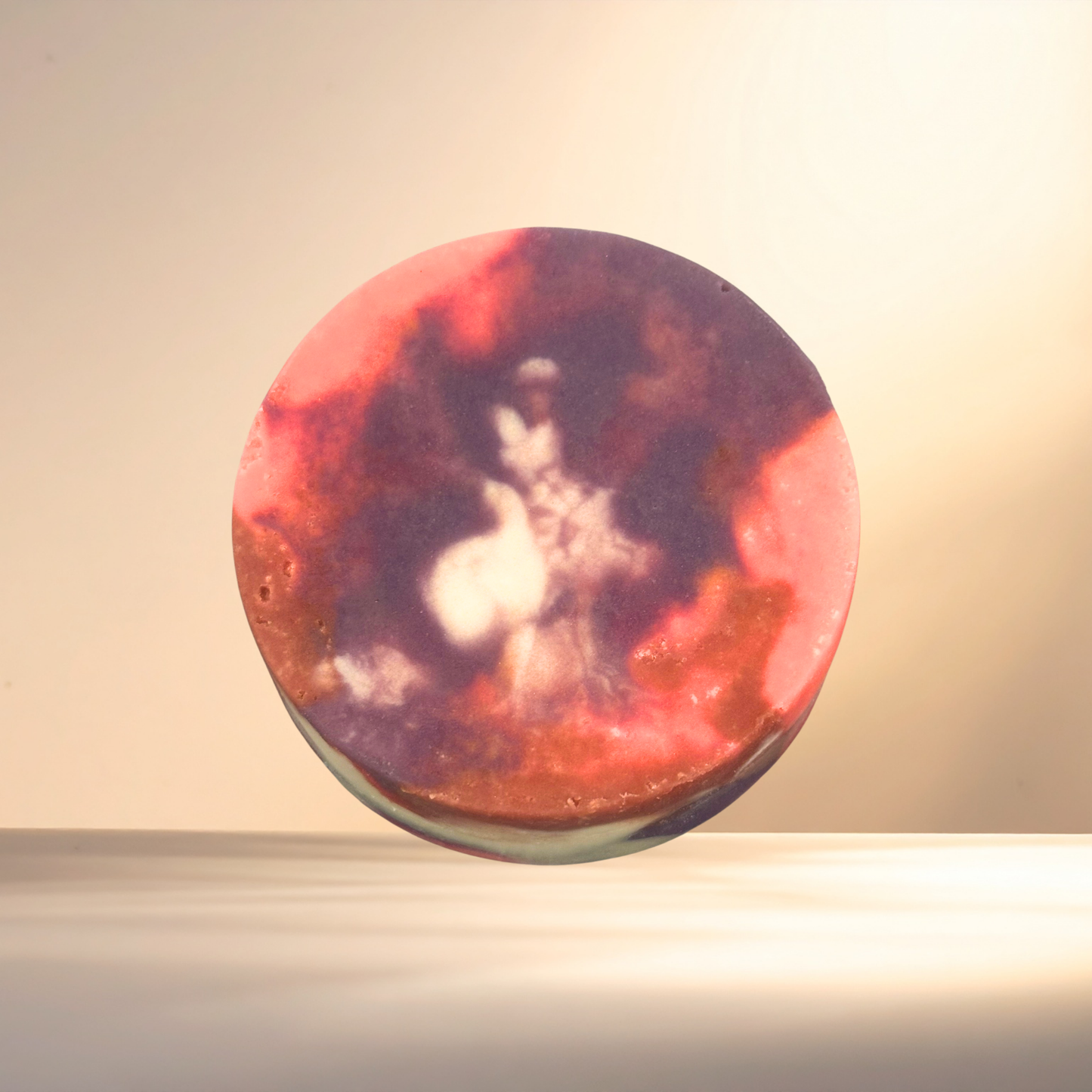 Round decorative soap with a red and purple design on a beige background
