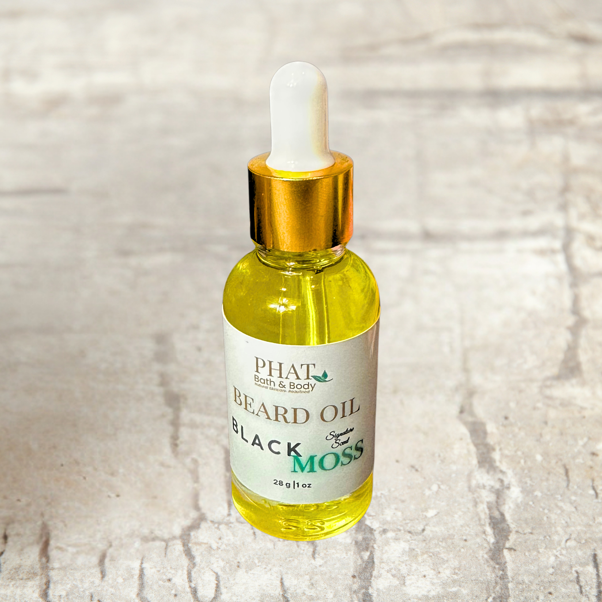 Bottle of Phat Bath & Body Black Moss Beard Oil on a textured surface