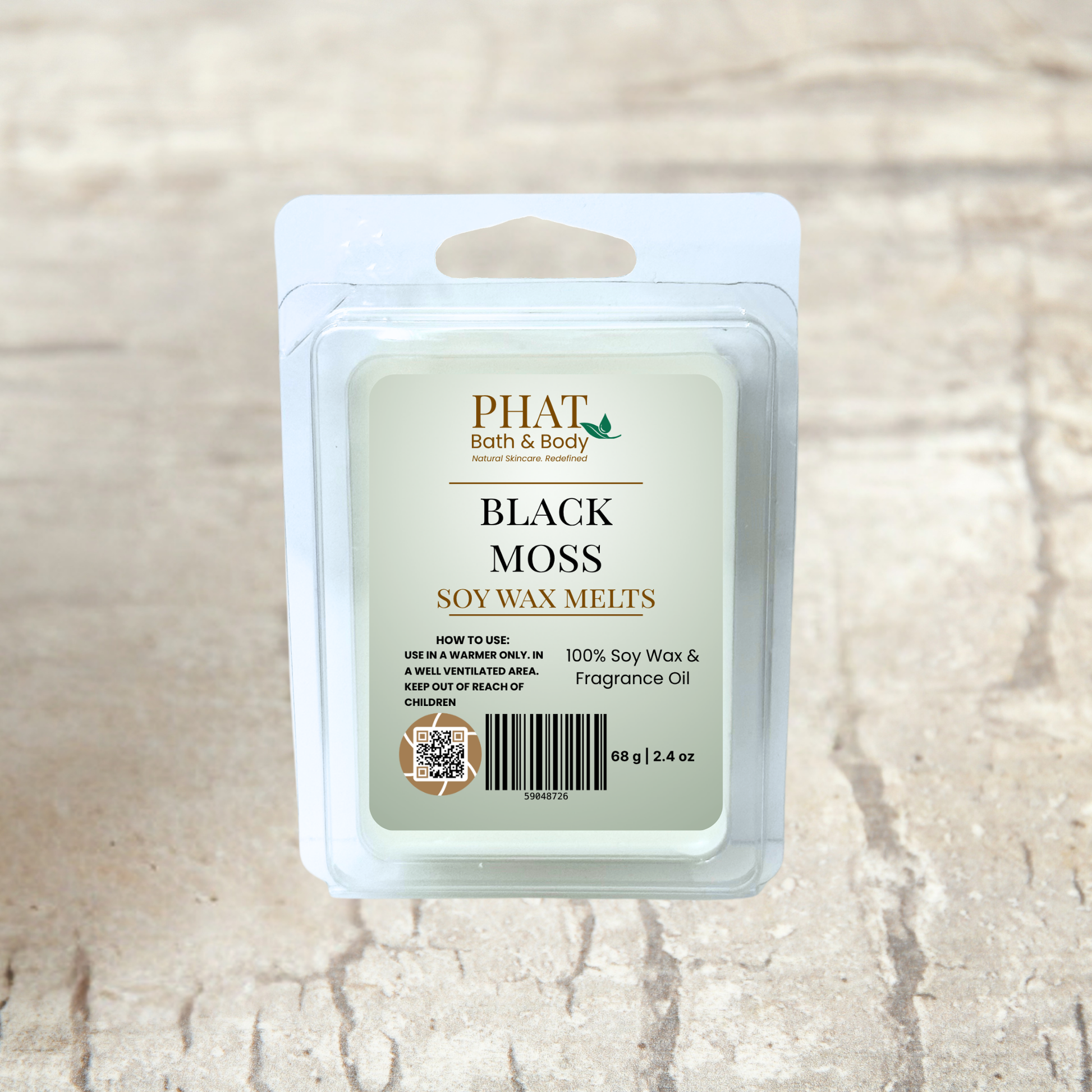Pack of Phat Bath & Body Black Moss soy wax melts on a beige fabric background with green leaves.