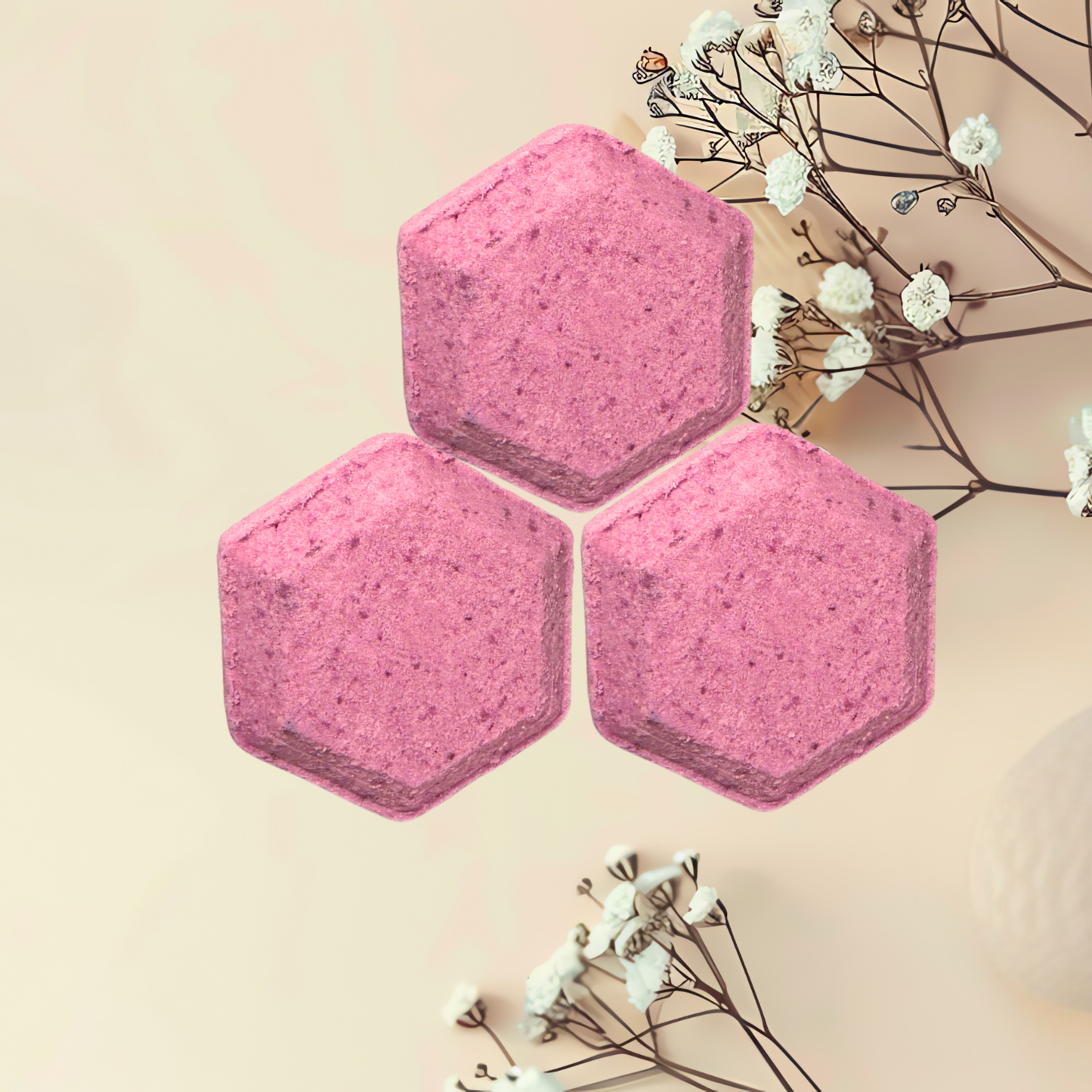 Three pink hexagonal shower bombs with white flowers on a beige background