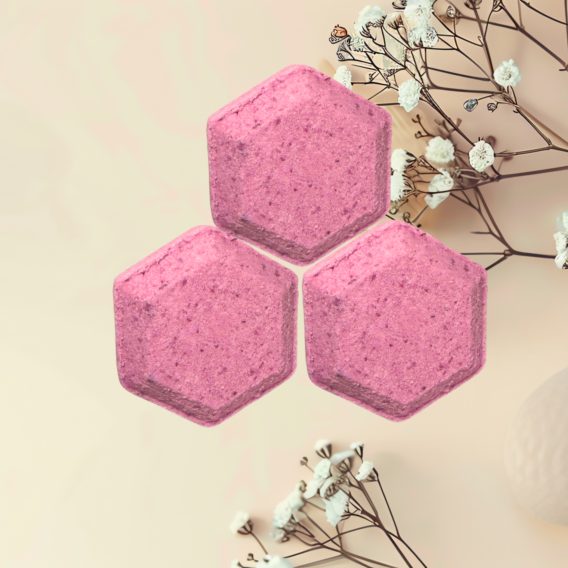 Three pink hexagonal shower bombs with white flowers on a beige background