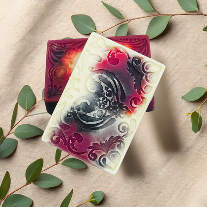 Decorative soap bars with intricate designs on a beige fabric background with green leaves.