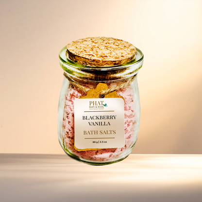 Jar of blackberry vanilla bath salts with a cork lid on a gradient background