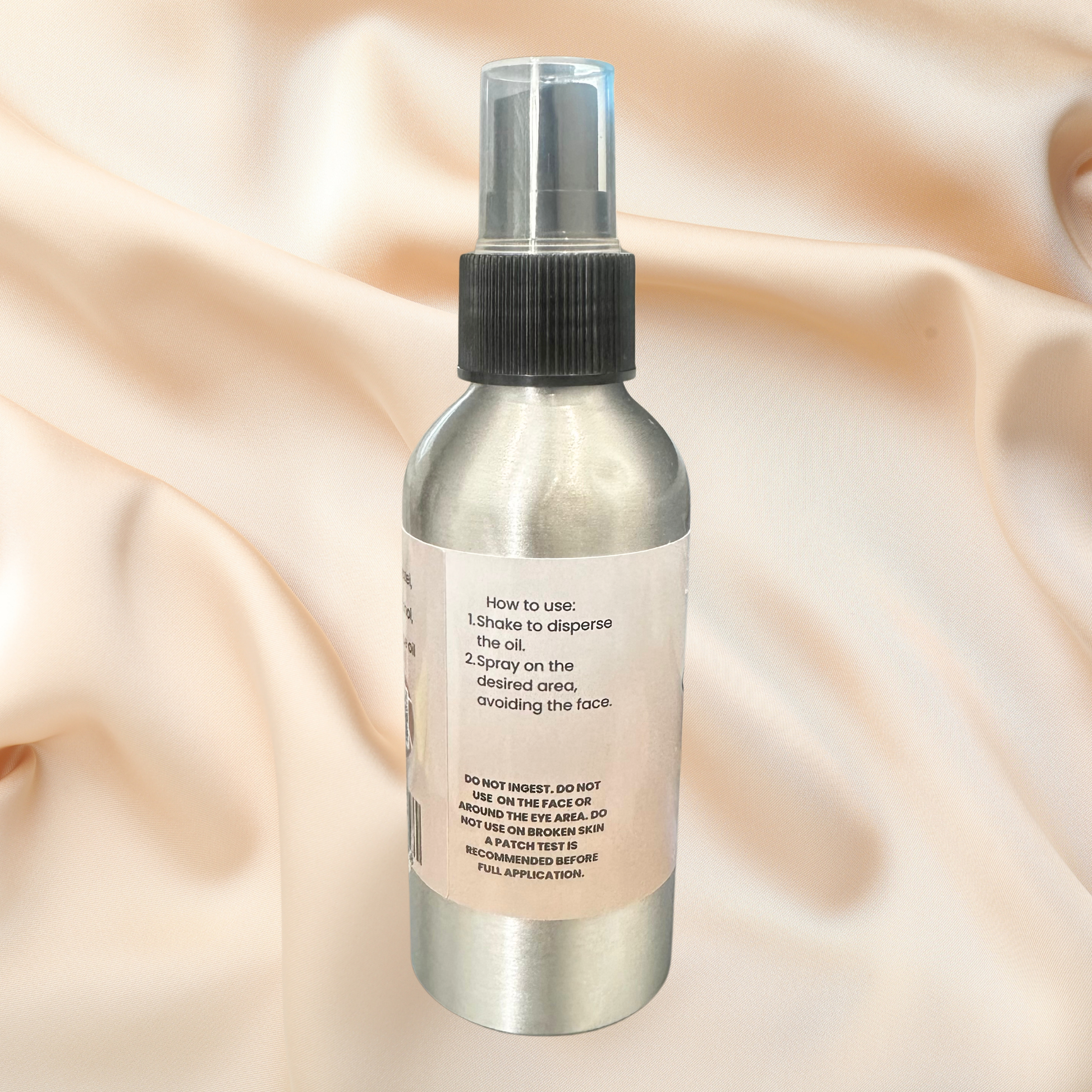 Body spray bottle with label on a beige fabric background