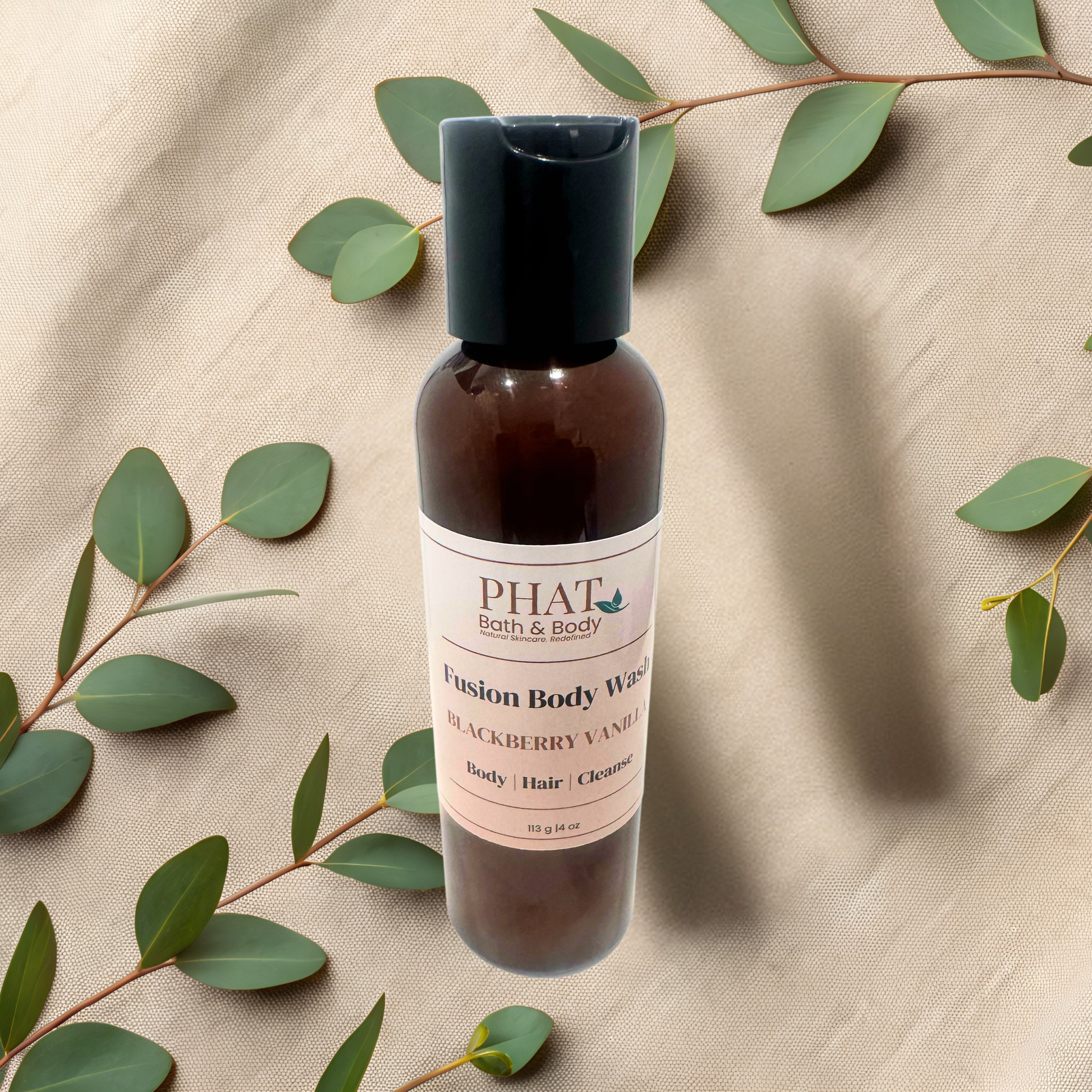 Bottle of Phat Bath & Body Fusion Body Wash on a beige fabric background with green leaves.