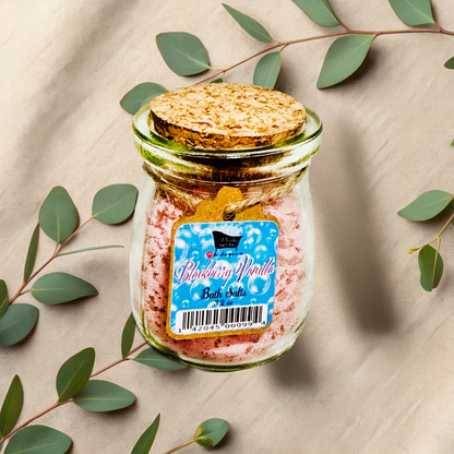 Jar of bath salts with a label on a beige fabric background with green leaves.