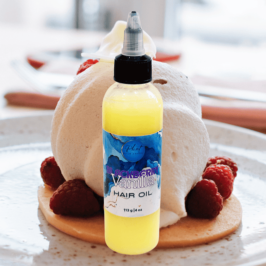 Bottle of Blackberry Vanilla hair oil on a dessert with raspberries