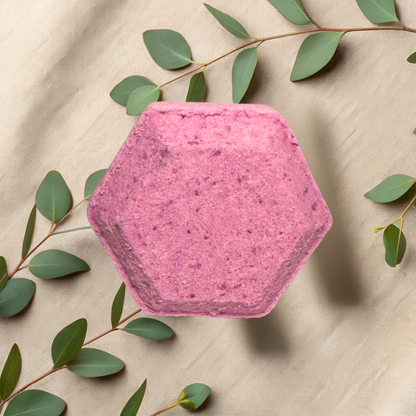Hexagonal pink shower bomb with green leaves on a beige fabric background