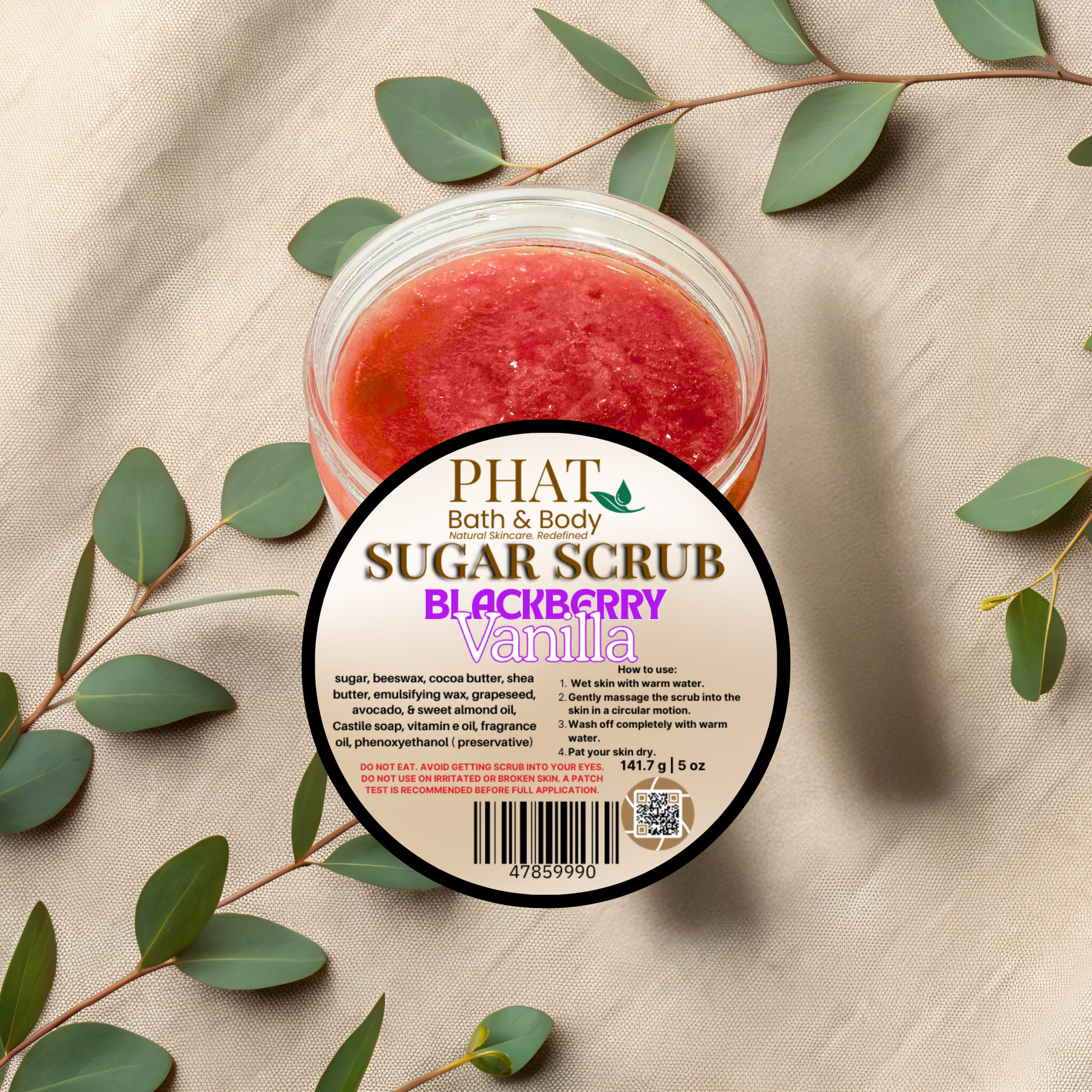 Jar of sugar scrub with blackberry vanilla scent on a beige fabric background with green leaves.